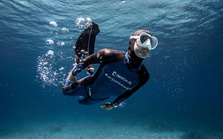 A male scuba diver underwater wearing a diving watch. 
