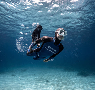 A male scuba diver underwater wearing a diving watch. 