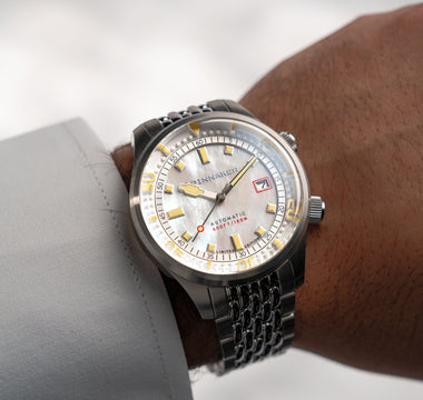 A man wearing a white shirt wearing a mother-of-pearl watch